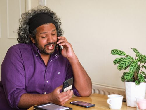 Dom smiling on the phone with several other testing devices scattered on the table